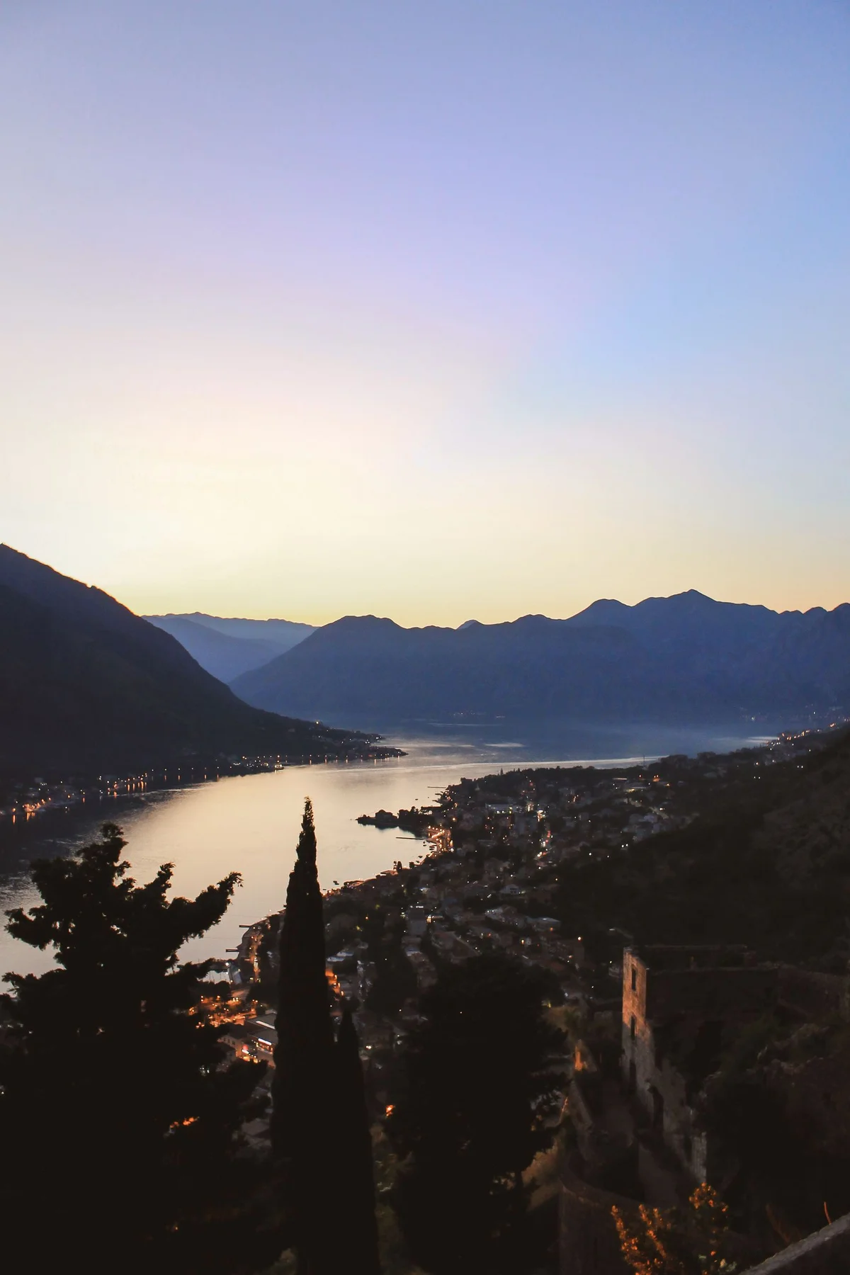 De Baai van Kotor in de schemering, met lichtjes langs het water en bergen